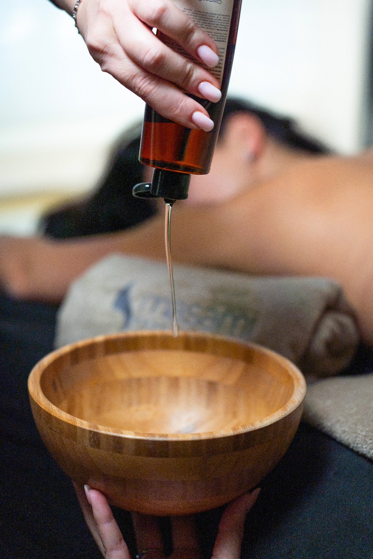 Olio da massaggio versato in una ciotola in bambù